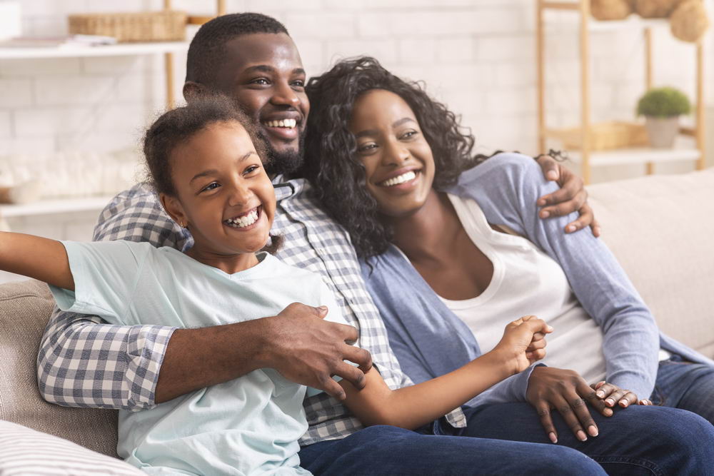 Joyful family relaxing on sofa at home, enjoying time together.